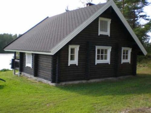 Jäniskylä6144度假屋的绿色田野上带白色窗户的黑色小房子