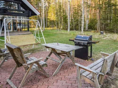 HerttualaHoliday Home Leporanta by Interhome的一张野餐桌和两张椅子,旁边是烧烤架