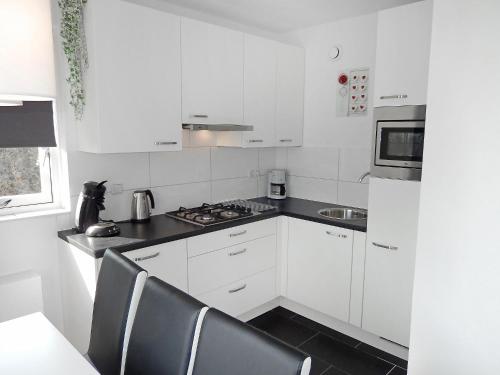 诺德克豪特Holiday Home de Witte Raaf-3 by Interhome的厨房配有白色橱柜和炉灶烤箱。