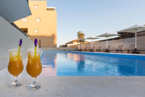 扎达尔Shell Luxury Residences with Pool and Whirlpool的坐在游泳池旁的桌子上喝两杯饮料