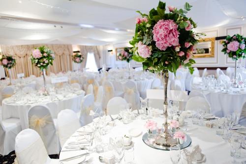 罗斯林奥兰吉尔罗斯格酒店的婚礼宴会厅配有白色桌子和粉红色的鲜花