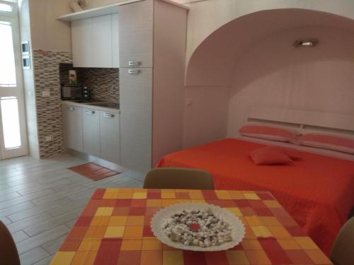 滨海波利尼亚诺GIUAMAR casa vacanza的一间卧室配有一张床铺和一张桌子,还设有一间厨房