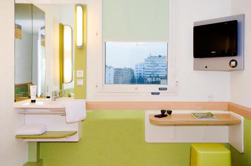 圣热尼拉瓦勒宜必思经济里昂南方圣格尼斯拉瓦尔酒店的一间带两个盥洗盆的浴室、一台电视和一个窗口