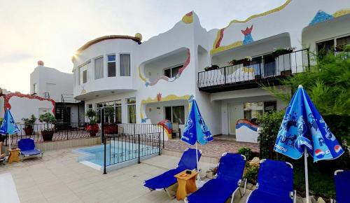 旧瓦马Hotel Laguna的房屋前设有带蓝色椅子和遮阳伞的天井。