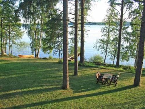 AhvionniemiHoliday Home Korvenvalkama by Interhome的两个长椅坐在湖边的草地上
