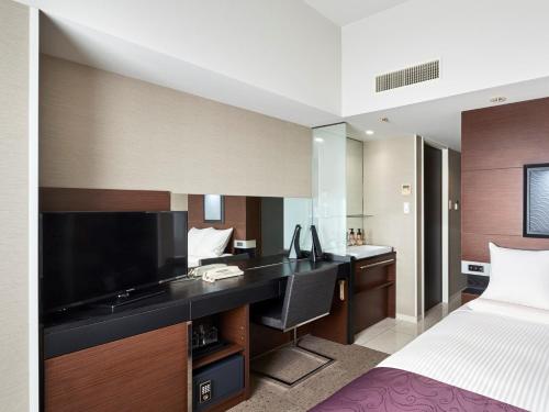 静冈HOTEL MYSTAYS Shimizu的一间卧室配有一张床和一张书桌及电视