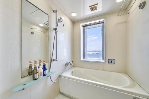静冈HOTEL MYSTAYS Shimizu的白色的浴室设有浴缸和窗户。