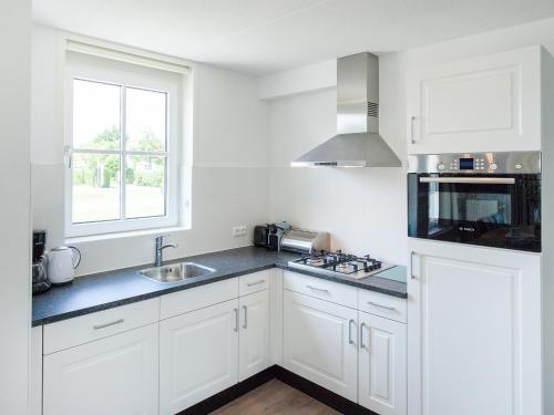 诺德克豪特Holiday Home de Witte Raaf-2 by Interhome的厨房配有白色橱柜、水槽和窗户。