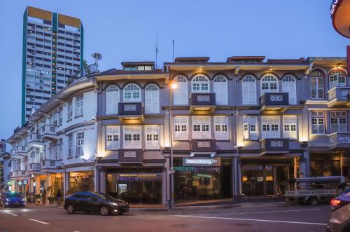 新加坡Butternut Tree Hotel的街道上的建筑物,前面有停车位