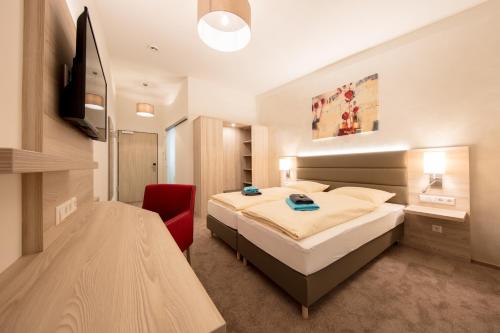里德林根Hotel Gudrun的一间卧室配有一张床和一张红色椅子