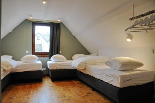 维尔雅尔姆Maison du Lac Vielsalm的阁楼间设有三张床和一扇窗户。