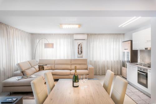 梅拉诺Fior Apartments Lofts的客厅配有沙发和一张桌子及一瓶葡萄酒