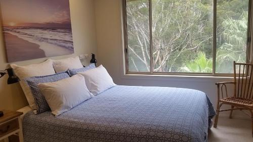 楠巴卡黑兹Nambucca Beach House的一间卧室设有一张床和一个大窗户
