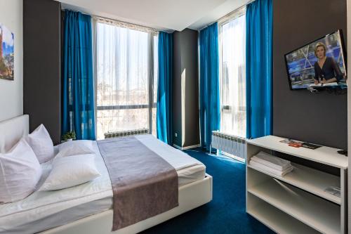 秋明Hotel England Tyumen Center的一间卧室配有一张带蓝色窗帘的大床