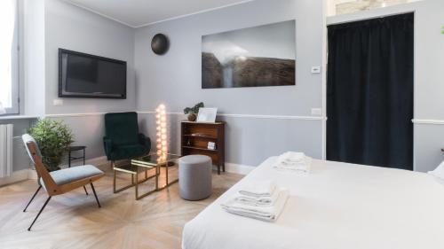 米兰Italianway - Garigliano 4 Flat的一间卧室配有一张床、两把椅子和一台电视