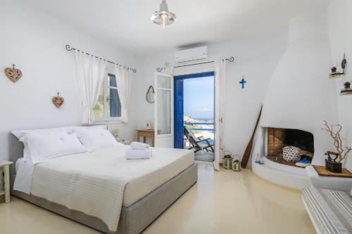Agia Kiriaki BeachHeavenly Milos suites的一间白色卧室,配有一张床和一个壁炉