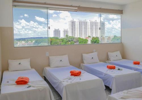 戈亚尼亚Hotel Cco Goiânia的带大窗户的客房内的三张床