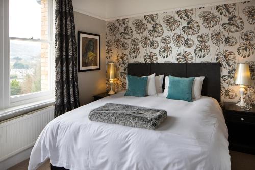 伊尔弗勒科姆诺伯里楼时尚旅馆的卧室配有带蓝色枕头的大型白色床