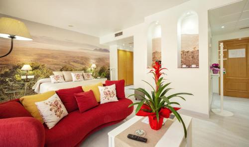 阿尔卡拉拉雷亚尔托瑞帕玛酒店的客厅配有红色的沙发和床。