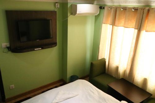 加德满都Hotel Samrajya Pvt. Ltd.的一间卧室配有电视、一张床和一把椅子
