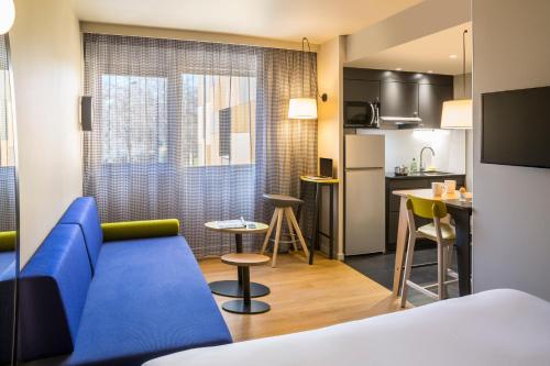 蒙彼利埃Aparthotel Adagio access Montpellier Centre的酒店客房设有蓝色的沙发和厨房。