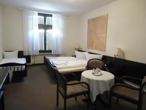 萨勒河畔哈雷玛莎酒店的一间设有四张床和两张桌子及椅子的房间