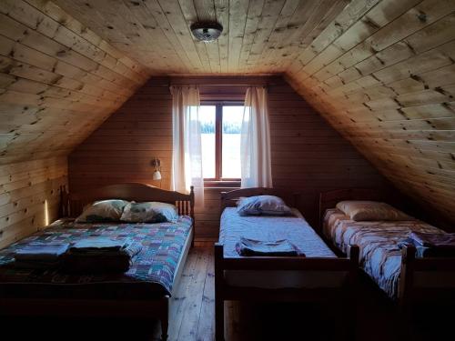 尤卡尔内Pirmie Zaļmeži的木间设有两张床,设有窗户