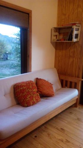 科伊艾科Cabañas Kuyen的一个带两个枕头的沙发,坐在一个窗户的房间