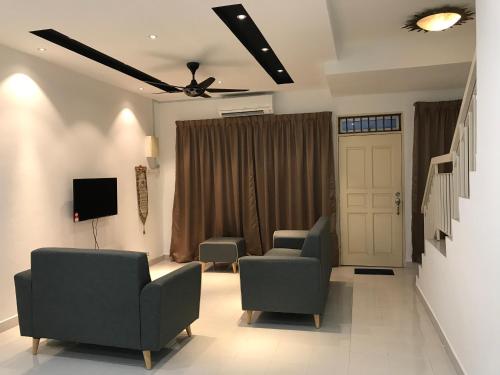 实达阿南NZAK Homestay, Bukit Bandaraya Seksyen U11的客厅配有两把椅子和电视