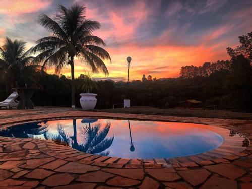 圣代佩德罗Hotel Paraíso Dos Alpes的棕榈树和日落背景的游泳池