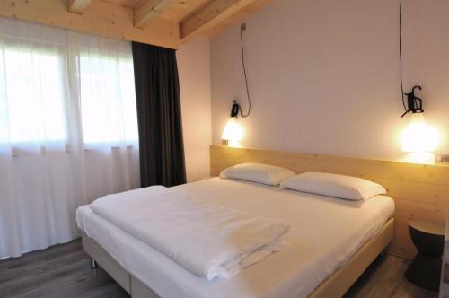 莫尔韦诺Bungalows Chalets Lago di Molveno的卧室配有一张带两个枕头的大白色床