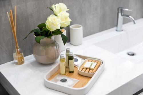 威尼斯San Zaccaria Apartment的浴室水槽配有两瓶肥皂和玫瑰花花瓶