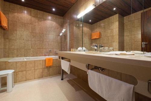 拜罗伊特金色赫西酒店的一间带大水槽和浴缸的浴室