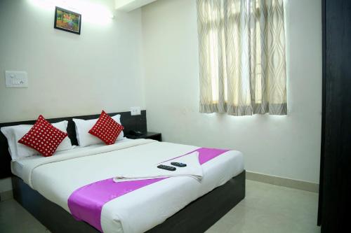 班加罗尔Orange Corner, Near Kempegowda Bangalore international airport的一间卧室配有一张带红色和白色枕头的大床