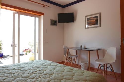 AlfeizerãoTir Na Nog的一间卧室配有一张床、一张桌子和一台电视