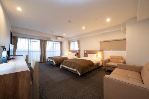 和歌山HOTEL CITY INN WAKAYAMA Wakayama-Ekimae的酒店客房,设有两张床和一张沙发