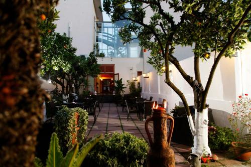 庞贝戴安娜酒店的一个带椅子和树木的庭院和一座建筑