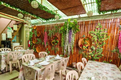马尼拉Conrado's Apartelle的餐厅墙上挂着桌椅和鲜花