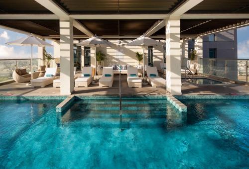 迪拜Millennium Atria Business Bay的一座大楼内的游泳池,配有椅子和遮阳伞