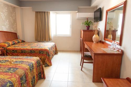 韦拉克鲁斯Hotel Impala -Atras del ADO的酒店客房设有两张床、一张桌子和一面镜子