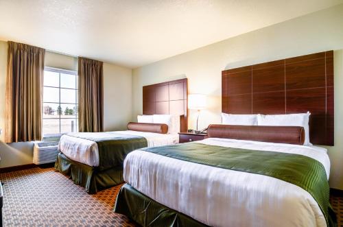 WintersetCobblestone Inn & Suites-Winterset的酒店客房设有两张床和窗户。