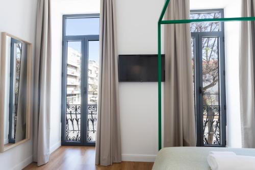 法鲁Alameda Exclusive House的卧室设有2扇窗户,墙上配有电视。