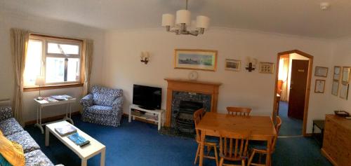 泰恩德拉姆Dalkell Cottage的客厅配有桌子和壁炉