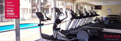 CabramattaRamada Hotel & Suites by Wyndham Cabramatta的游泳池旁的健身房设有一排跑步机