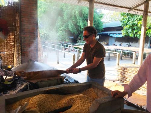 芹苴Mekong Farmstay CanTho - C.R Floating Market的一个人在烧烤架上做饭