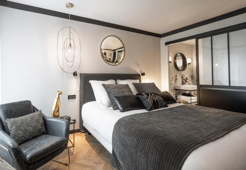 南特Maisons du Monde Hotel & Suites - Nantes的一间卧室配有一张床、椅子和镜子