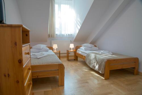 克拉科夫圣西蒙大教堂民宿的一间卧室设有两张床、一个梳妆台和窗户。