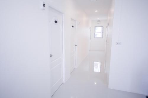 曼谷U-need Guesthouse95的白色的走廊,设有白色的墙壁和窗户