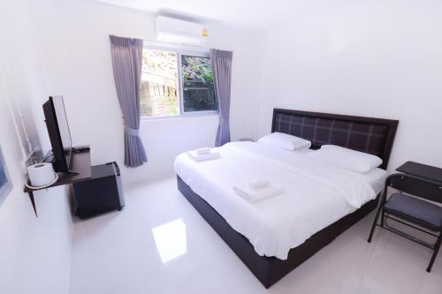 曼谷U-need Guesthouse95的白色卧室设有一张大床和电视。