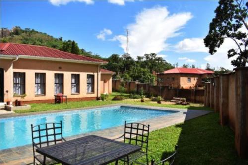 ZombaWadonda Suites的一座带游泳池和桌椅的房子